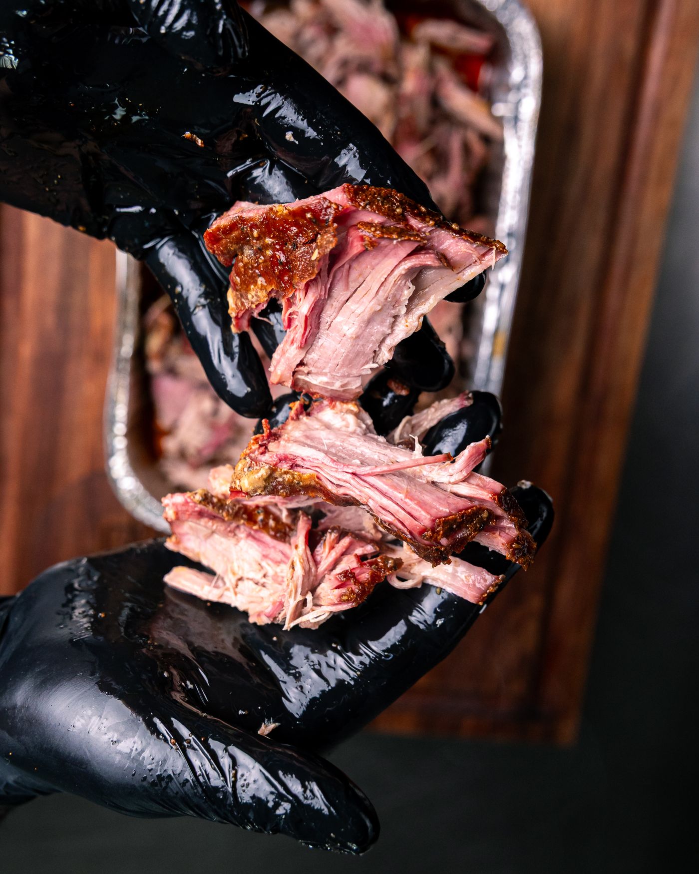 Hands pulling apart tender smoked brisket